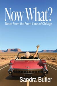 Woman waving from a red convertible in a desert landscape under a blue sky.